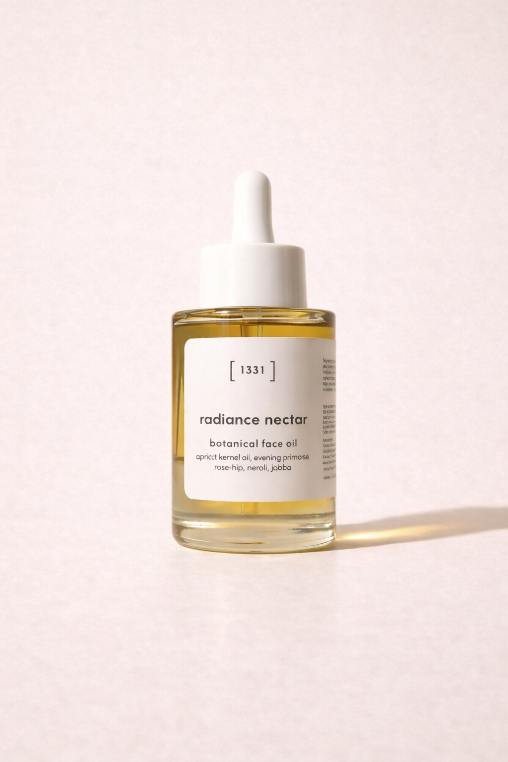 Bottle of radiance nectar botanical face oil on a light pink background
